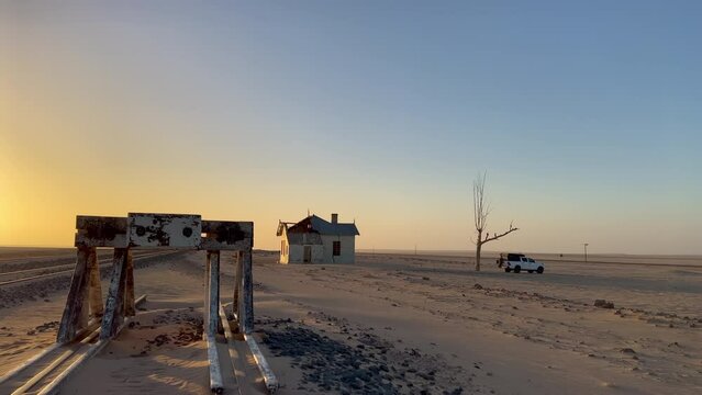 SUV 4x4 car parked near dried dead tree and Garub railroad station. Kolmanskop.