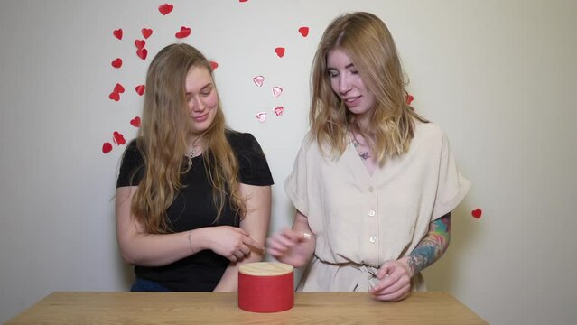 The girl gives her friend a condom in a gift box