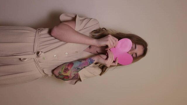The girl smiles and shows a pink valentine and kisses her