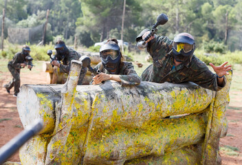 Portrait of man and woman paintball players in full gear on playing field