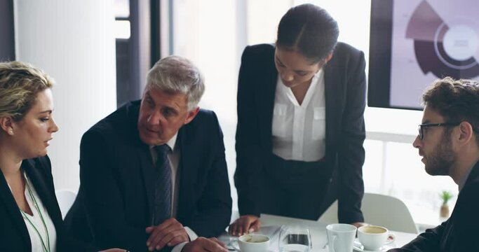 Getting proactive about success. Business man in suit talking to colleagues sitting at conference table. Mature boss discussing group work at team meeting in the boardroom in a modern office