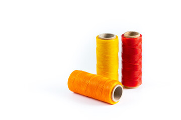 A skein of red, orange and yellow thread. Coils of colored threads on a white background. Waxed sewing thread for leather goods.