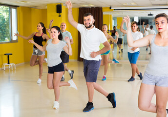 Positive people are dancing boogie-woogie in pairs in modern studio.