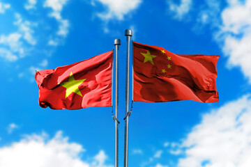 Flags of Vietnam and China on the wind against blue sky
