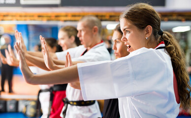 Women and man in kimono training kata movements during group karate classes. © JackF