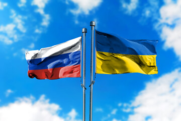 Flags of Russia and Ukraine on the wind against blue sky
