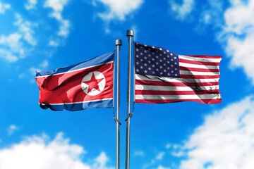 Flags of North Korea and America on the wind against blue sky