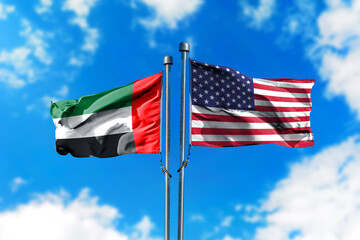 Flags of United Arab Emirates and America on the wind against blue sky