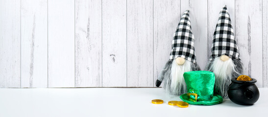 St Patrick's Day farmhouse theme background banner backdrop. Styled with green leprechaun hat and buffalo plaid gnome against a white wood background. Negative copy space.