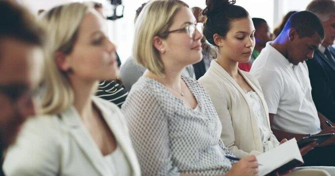 Diverse audience of businesspeople at a conference. Businesspeople making notes while attending a seminar. Training audience participants sitting with notebooks and listening to speaker 