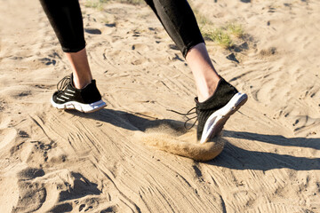 feet in sneakers running along the sandy beach. running activity. running on the sand.