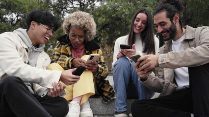 Group of four friends watching something funny at mobile cell. Happy people using phone and having fun