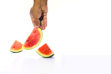 Close-up view of an Asian man's hand is picking up a fresh ripe watermelon slice isolated on white background. Tropical fruits, healthy eating, and summer background concept.