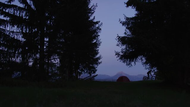 A cyclist departs his camp site at dusk