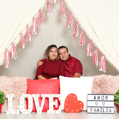 Latin Hispanic adult couple demonstrate love under a teepee with a sign that says 