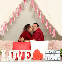 Latin Hispanic adult couple demonstrate love under a teepee with a sign that says 