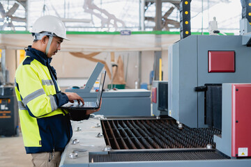 Fototapeta premium Asian male industrial engineer using laptop He made a gesture while working in a heavy industrial factory.