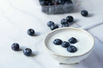 fresh blueberry yogurt in white cup on marble background