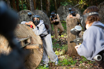 Fototapeta premium Group of people in full gear playing paintball on shooting range