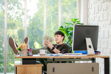 Rich entrepreneur happy to count money in hands earning from successful cash flow growth of business finance while relaxing with smile in company office