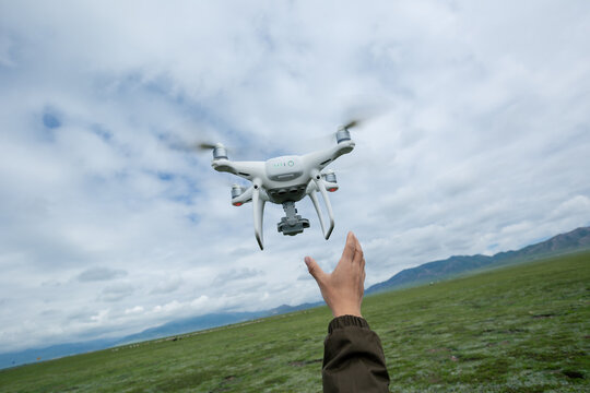 Hand reaching for a flying drone taking picture in Tibet,China