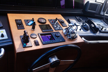 Luxury yacht cockpit with dashboard, various buttons and switches, steering wheel, acceleration...