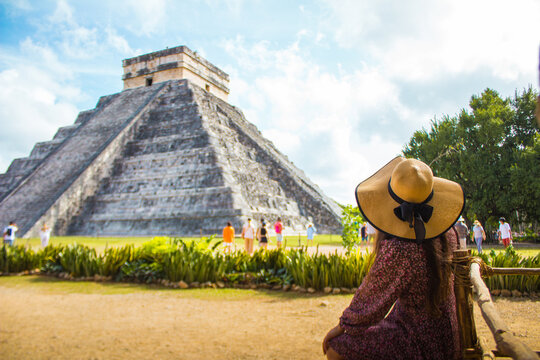 Hermosa foto de una chica sentada viendo la piramide de chichen itza al fondo