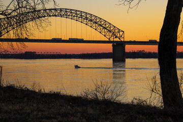a stunning shot of a white motor boat sailing down the Mississippi river with a gorgeous yellow and...