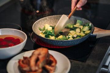 Woman stirring vegetables on frying pan. Close up of unrecognizable woman preparing lunch in the kitchen.