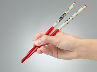 hand with pair of chopsticks