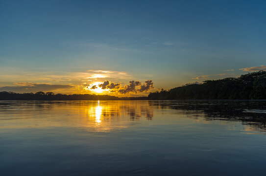 Sunset on the Amazon river during a boat trip with a reflection of the trees in the water, Pastaza province, Ecuador.
