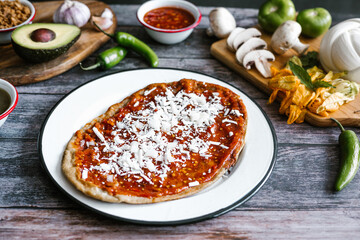 Memela sope quesadilla poblana of red sauce with cheese, onion and avocado traditional mexican food from Puebla, Mexico