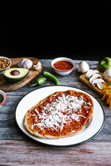 Memela sope quesadilla poblana of red sauce with cheese, onion and avocado traditional mexican food from Puebla, Mexico