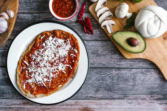 Memela sope quesadilla poblana of red sauce with cheese, onion and avocado traditional mexican food from Puebla, Mexico