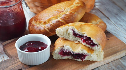 Сherry Pies stuffed with berries cherry, bowl with cherry jam. Homemade sweet pies from yeast dough freshly  baked in oven