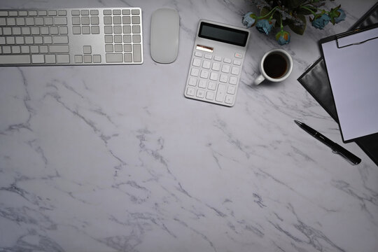 Top view calculator, coffee cup and wireless keyboard on marble background.