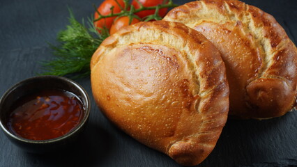 Latin American fried empanadas with tomato sauce. Argentinian Empanada is a pastry turnover filled with a variety of savory ingredients and baked or fried.