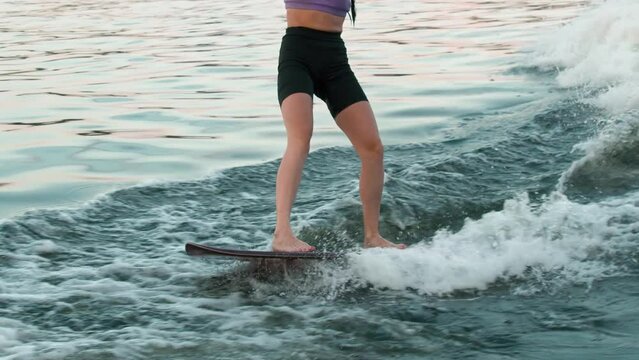 A female surfer jumping on a wakeboard. An experienced wakeboarder splashes water drops into the camera.