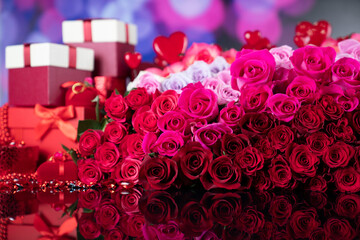 Valentines day theme. Gifts in boxes, red hearts and big bouquet of natural roses on blue bokeh background.
