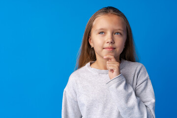 Little girl thinking and looking up over blue background