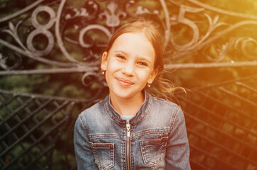 portrait happy smiling candid eight year old kid girl face sits on bench in nature. prepubertal age of children and lives, mind psychology and mental health. fashion clothes. geometric shapes. flare