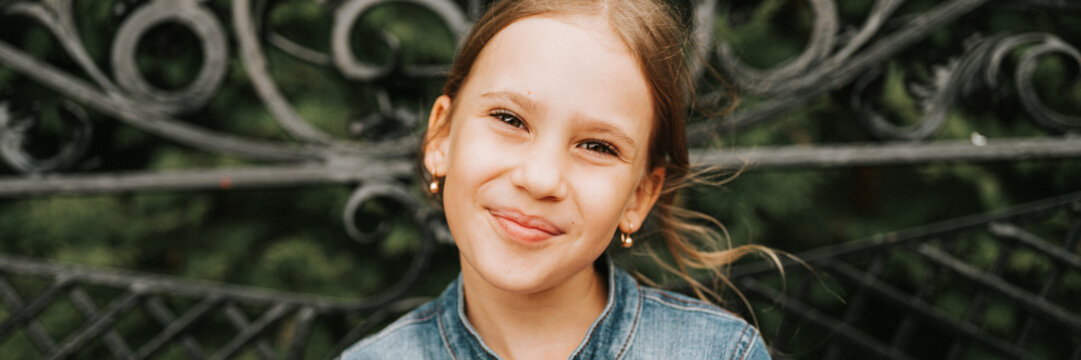 portrait happy smiling candid eight year old kid girl face sits on bench in nature. prepubertal age of children and lives, mind psychology and mental health. fashion clothes. geometric shapes. banner