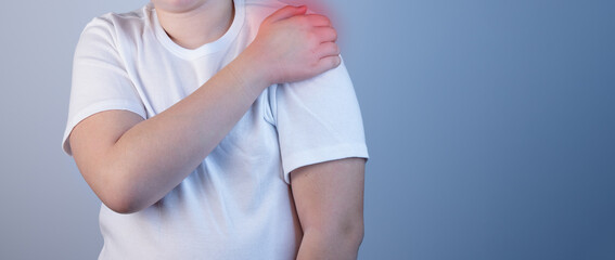 A young man suffering from shoulder pain. Concept disease. Pain in the shoulder joint, muscle pain. Pain in the shoulder joint. The cause of the disease is tension, stress or injury. Copy Space
