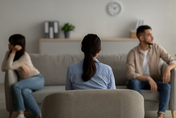 Back view of female psychologist giving therapy session to quarreling arab couple at office, helping them with conflict - obrazy, fototapety, plakaty