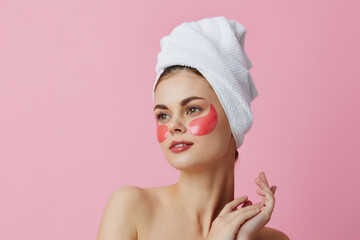 young woman pink patches on the face with a towel on the head pink background