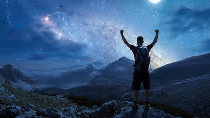 Hiker in the mountains under a starry night sky