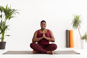 Beautiful plus size black woman doing yoga exercise at studio