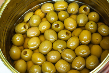 Pitted green olives in brine in an open tin. Pickled olives without pits.