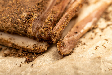 A piece of homemade bacon with pepper on white oiled paper, close-up, selective focus.
