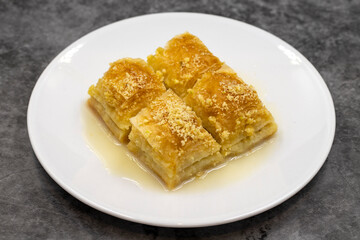 Baklava with milk (sutlu nuriye). Baklava with hazelnut and milk on a dark background.